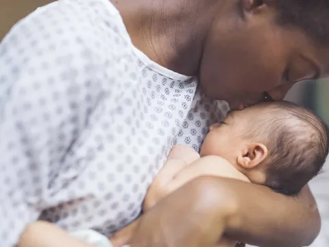 A mother kissing her newborn child