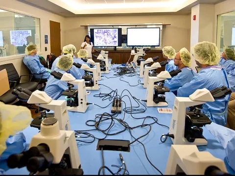 Professionals attending a lecture with microscopes in a Nicholson Center Lab Boardroom.