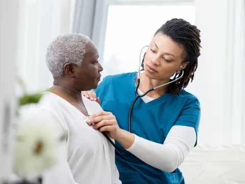 Nurse checking a woman patient's heartbeat.