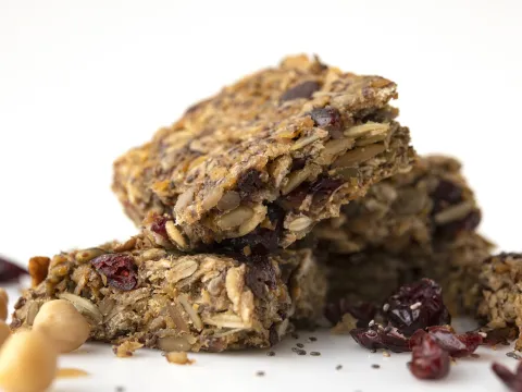 Four stacked square energy cookies next to garbanzos and raisins