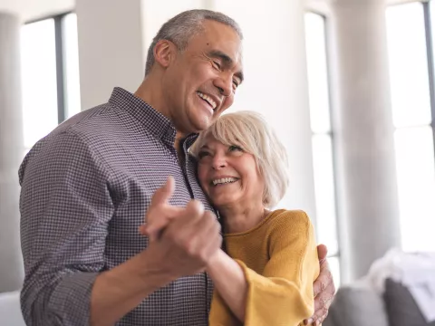 Older Couple dancing together while at home.