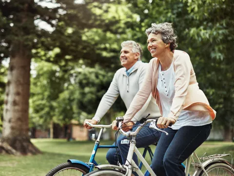 Older couple riding bicycles outdoors.