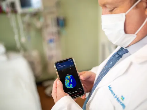 Physician holding a smartphone with a brain scan on screen.