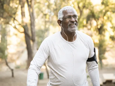 Older African American man walking outdoors.
