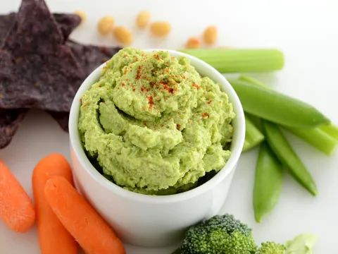 Side dish of edamame hummus with some carrots and chips