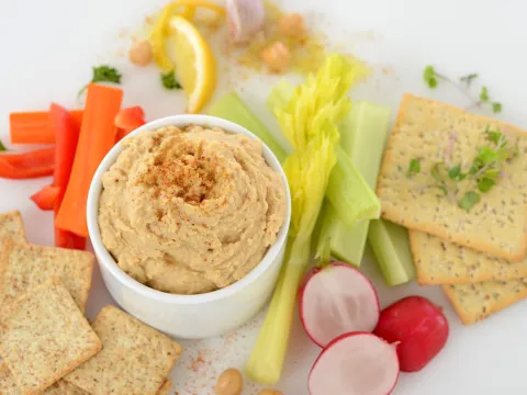 Dish of garmanzo hummus surrounded by crackers and vegetables