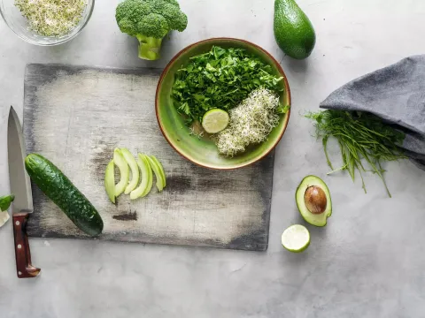 Salad bowl, produce, cutting board, towel and knife sitting on a counter.