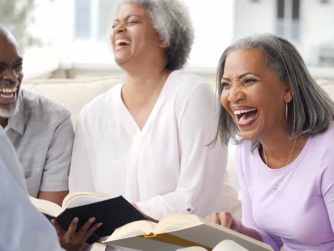 A group of older adults laughing while in a Bible study together.