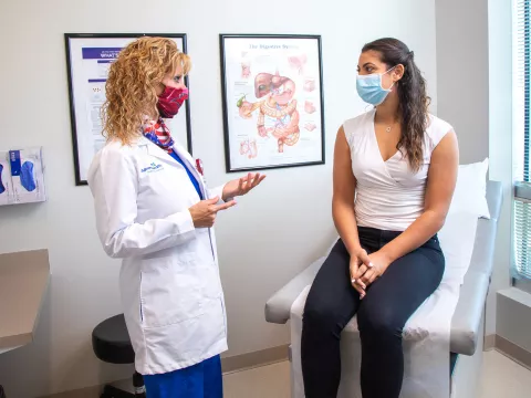 Doctor Sharona Ross talking with patient while wearing masks.