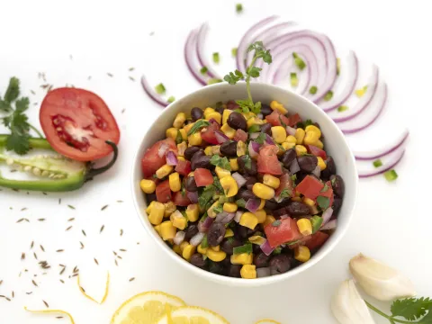 Bowl of black bean salad with vegetable garnishes