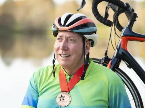 Man wearing a medal standing with his bike