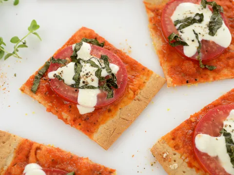 Four square pieces of margherita pizza with green garnish.