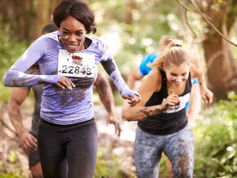 Two Women are running on a trail outside.