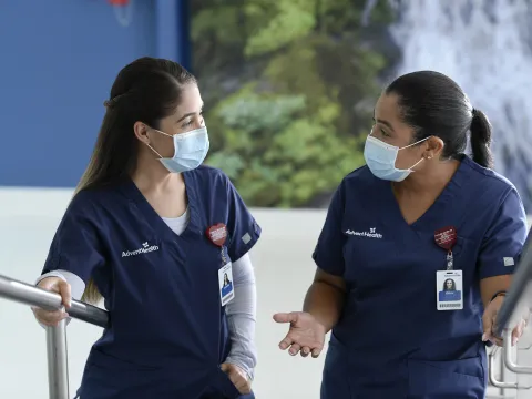 two masked female nurses walking up stairs talking to each other