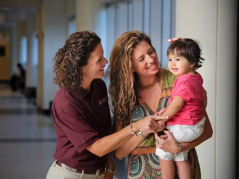 Two woman holding a child.