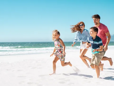 A happy family running together on the beach.