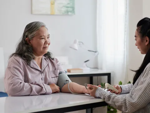 Adult daughter checking senior mother's blood pressure.