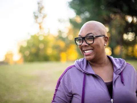 A woman smiles while at a park.