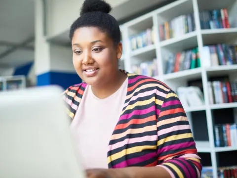 A young, female adult using her laptop while at a library