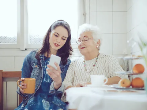 A young woman with an older women checking a cell phone