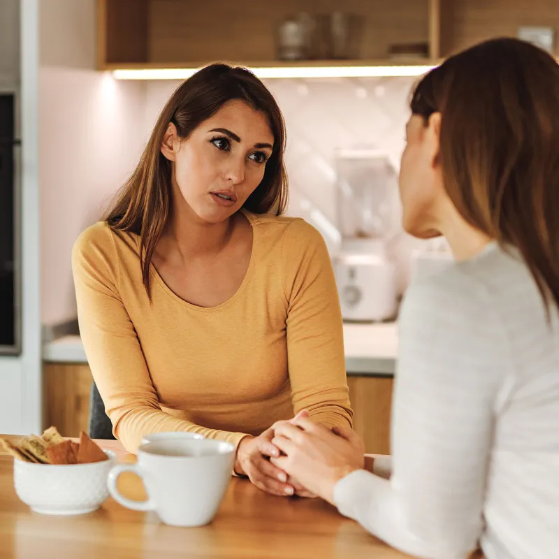 A Woman Comforts Her Friend in a Kitchen Over a Cup of Coffee