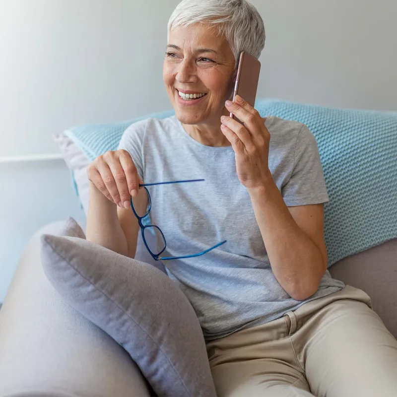 A woman on her cell phone at home on her couch. 