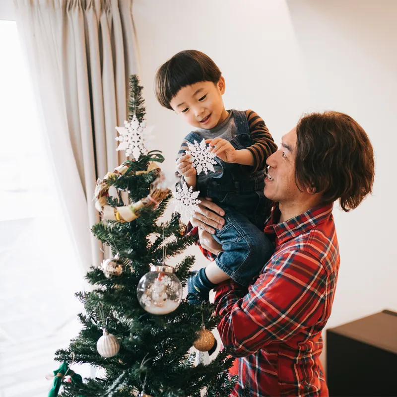 Father and son decorating a Christmas tree.