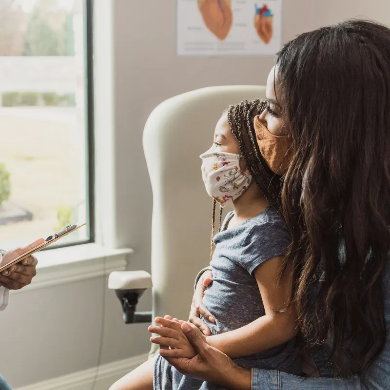 Doctor speaks to mother and child in a patient room.