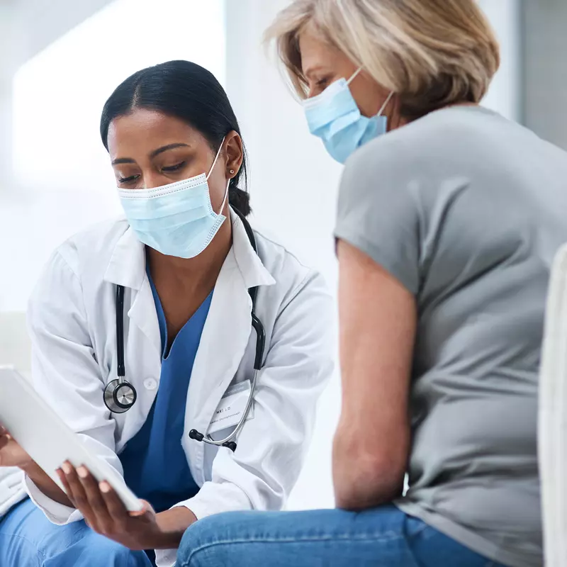 Doctor speaks to her middle aged female patient while going over some notes. 