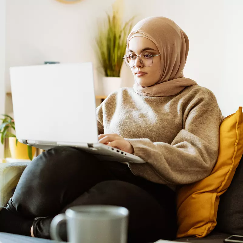 A Woman Looks at a Laptop Computer on Her Couch.