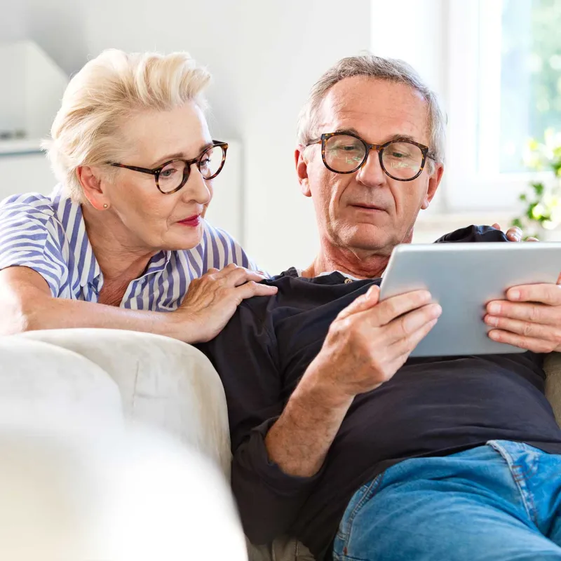 A senior couple focused on the tablet they carry