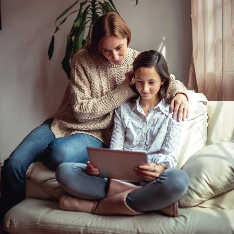 A mother and daughter reading from a tablet