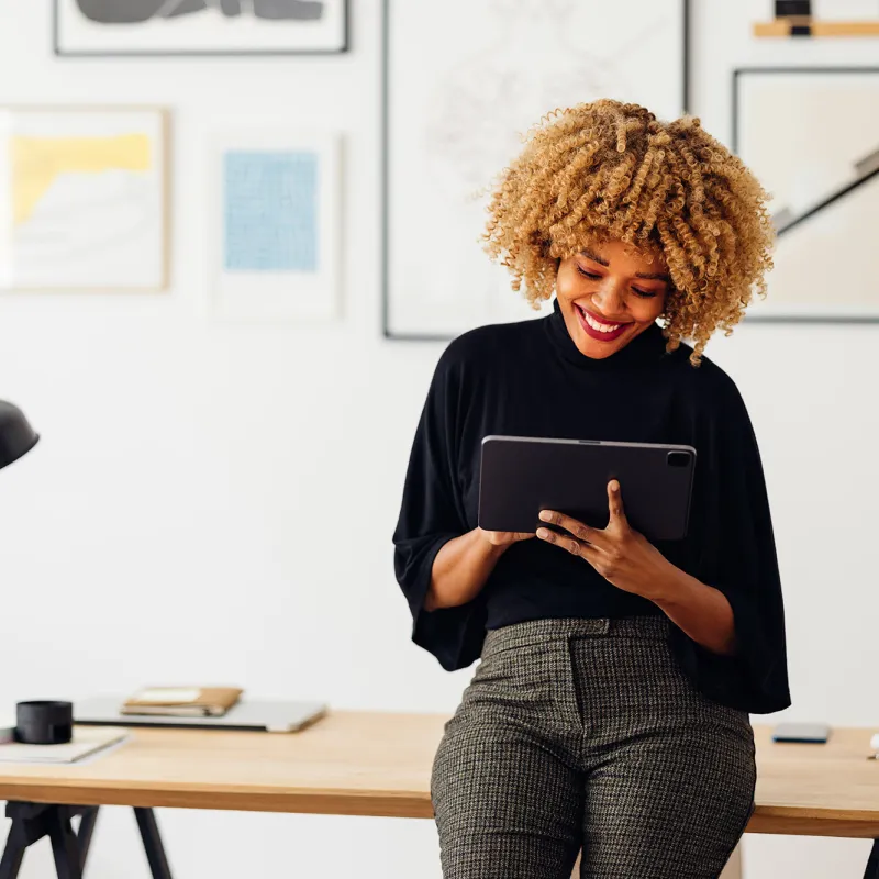 A slender, African American woman using a tablet at her office