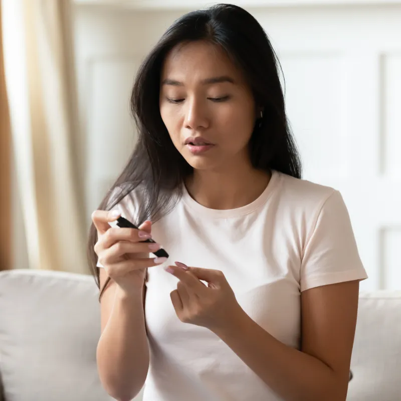A Woman Tests Her Glucose Levels with a Finger Medical Device