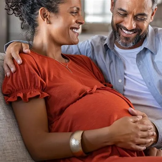 Pregnant couple sitting on couch