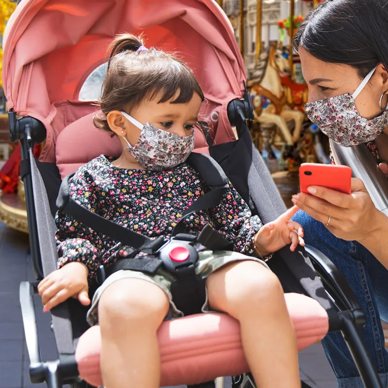 A mom and her young daughter wearing masks at a theme park.