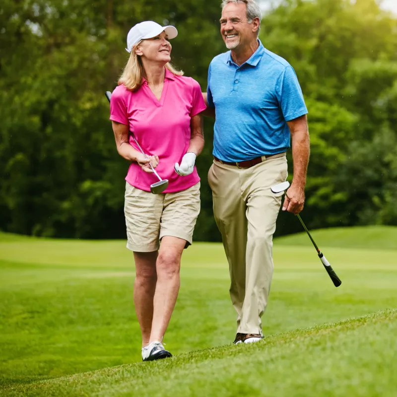 A senior couple, walking on a golf course.