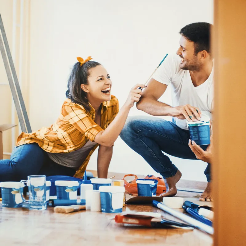 A couple, surrounded by paint cans.