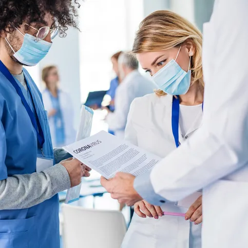 physicians wearing masks while looking at paper