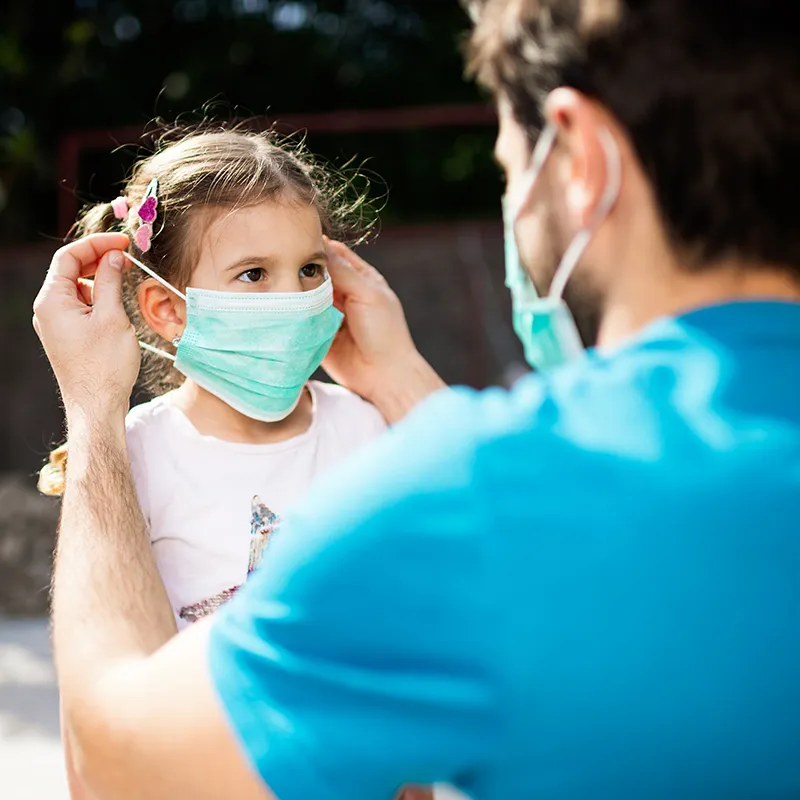 Dad putting mask on daughter 