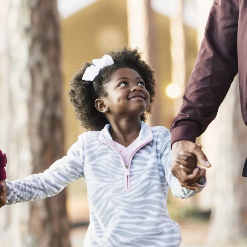 Young girl walks with her parents at the park