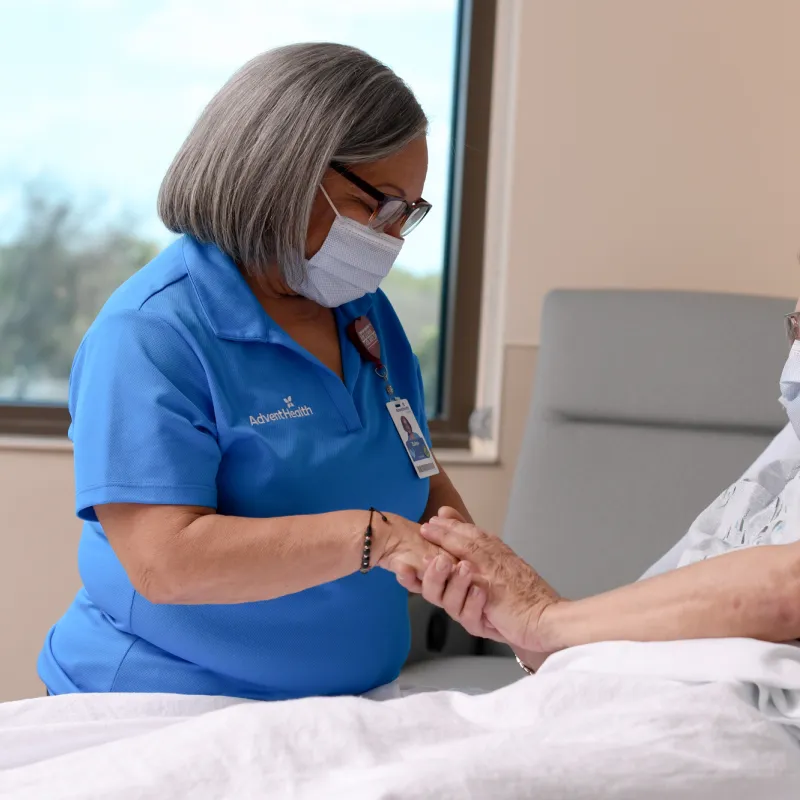 A Female Volunteer Prays with a Patient in a Hospital Room