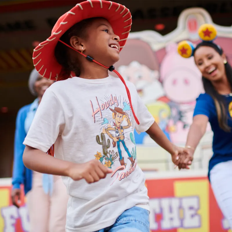 A mother holding her child's hand at a theme park.