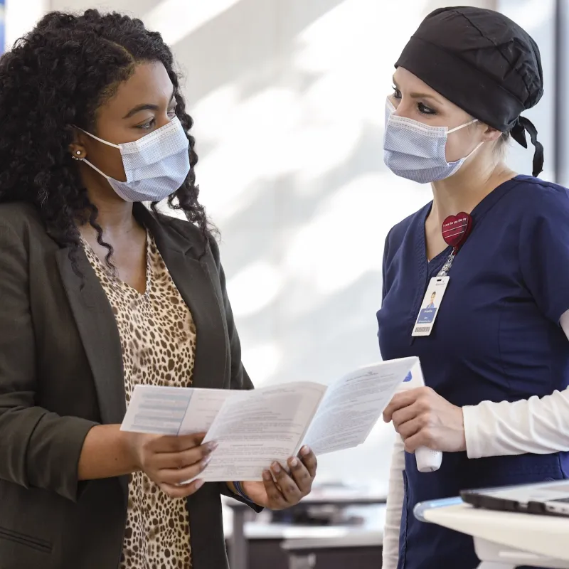 An AdventHealth employee assisting a patient with medical information