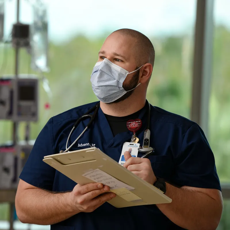 AdventHealth nurse writing on his clipboard