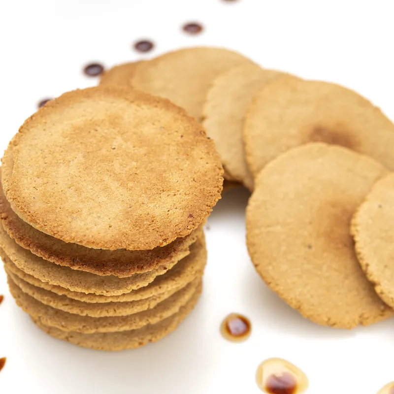 16 round, flat, golden cookies on a white surface