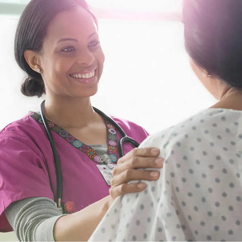 Female nurse comforting a female patient.