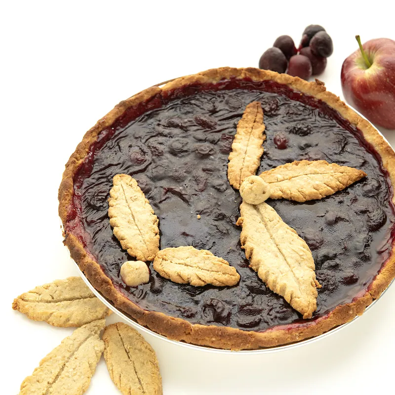 Whole cherry pie with apple, grapes, and leaf-piecrust garnishes