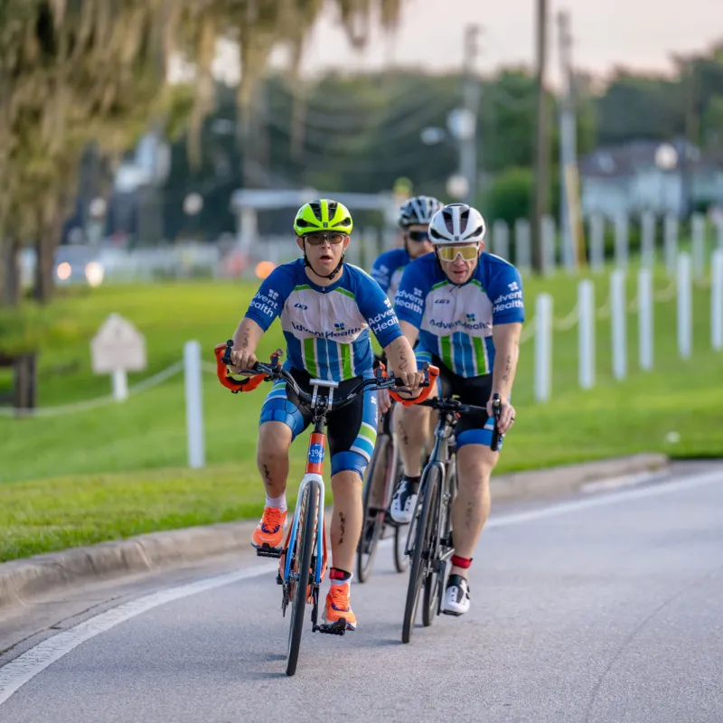 Triathlon participant, Chris Nikic, and his physical therapist, Trevor Hicks, biking on the road