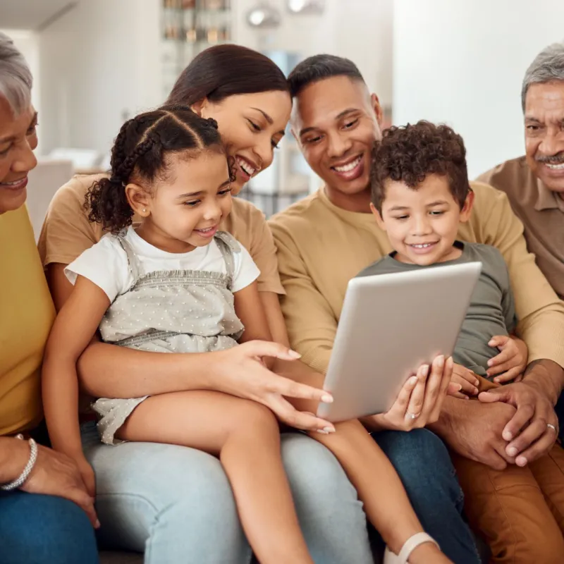 Hispanic Latino family on couch looking at iPad together 